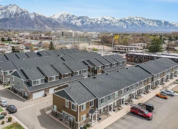 A large building complex with a parking lot in front and snow-capped mountains in the background.