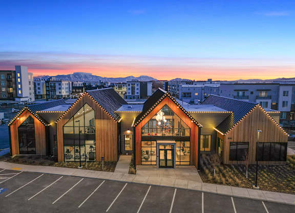A building with a wooden exterior and a large glass window is surrounded by a parking lot.