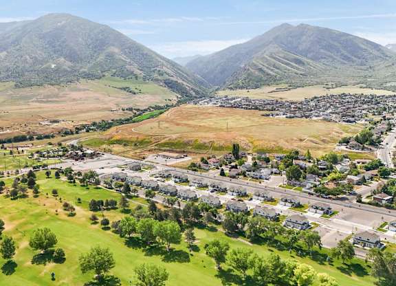 A small town is nestled in a valley with mountains in the background.