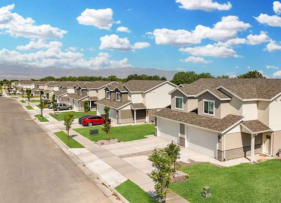 A row of houses with a red car parked in the driveway of the first house.