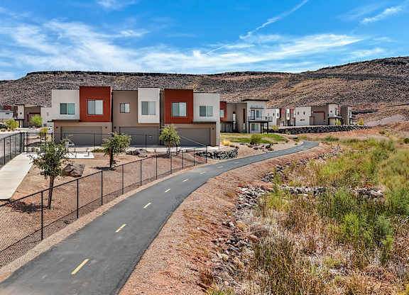 A road with a fence on the side and houses in the background.