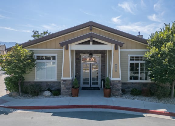 the front entrance of a tan house with a driveway and trees at Aldara Apartments in Saratoga Springs, Utah