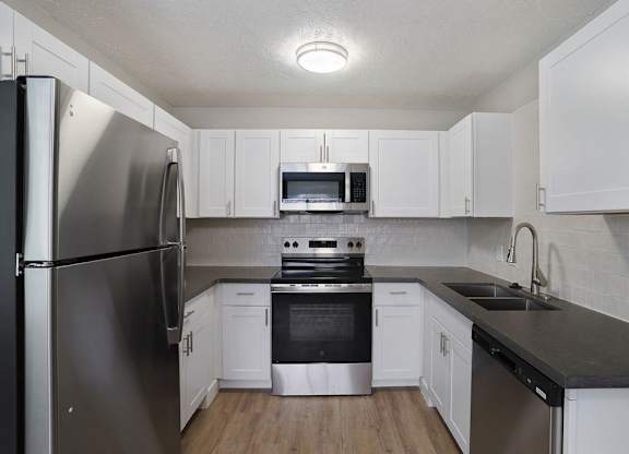 A kitchen with white cabinets and a black countertop.