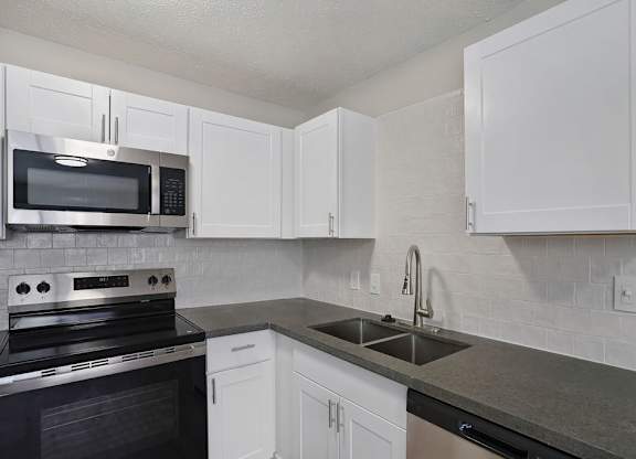 A kitchen with white cabinets and a black stove top oven.