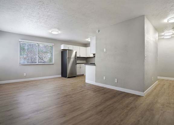 A kitchen area with a refrigerator, cabinets, and a window.
