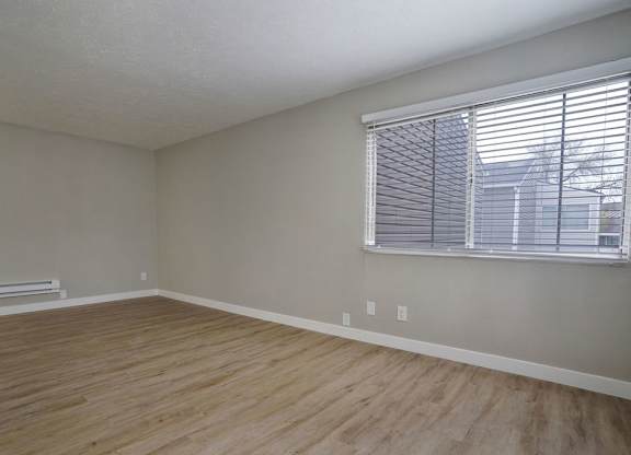 A room with wooden flooring and a window with blinds.