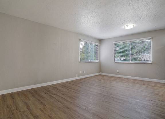 A room with wooden floors and two windows.