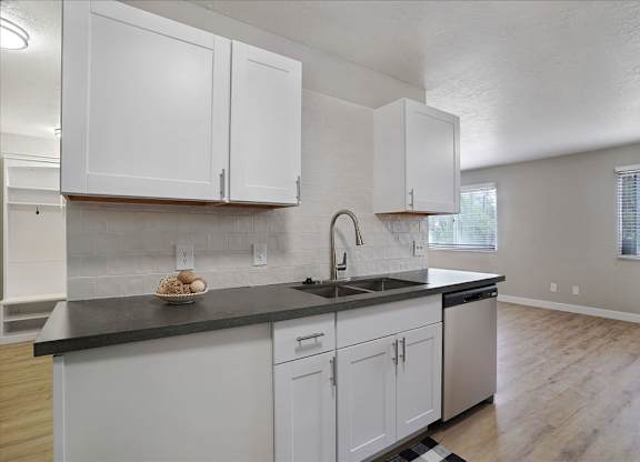 A kitchen with white cabinets and a black countertop.