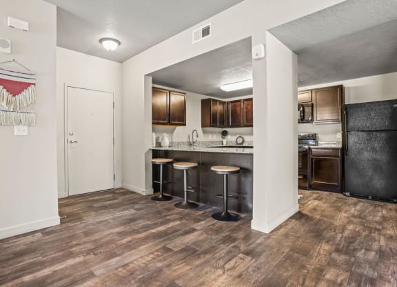 a kitchen with a bar with stools and a refrigerator