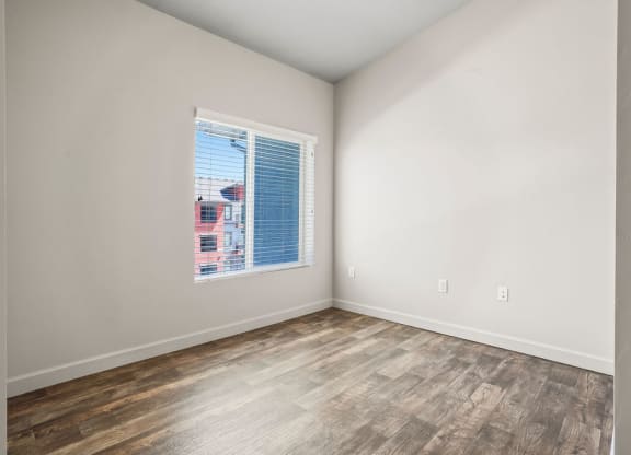 an empty room with a window and wood floors