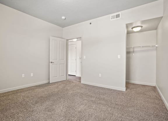 an empty living room with a closet and a door to a hallway