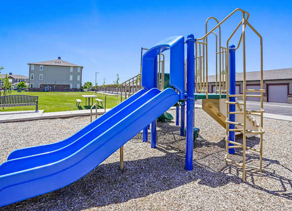 A blue slide in a playground with a yellow structure next to it.