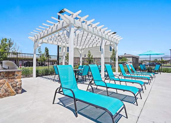 A row of blue chairs are lined up under a white pergola.