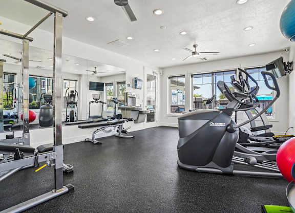 A spacious gym with a variety of equipment including a treadmill, weights, and a bench press.