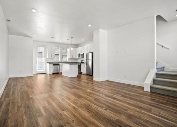 an empty living room with a kitchen and stairs  at Aero Luxury Townhomes in Layton, Utah