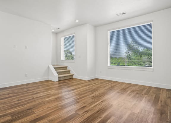 an empty living room with wood floors and a large window  at Aero Luxury Townhomes in Layton, Utah