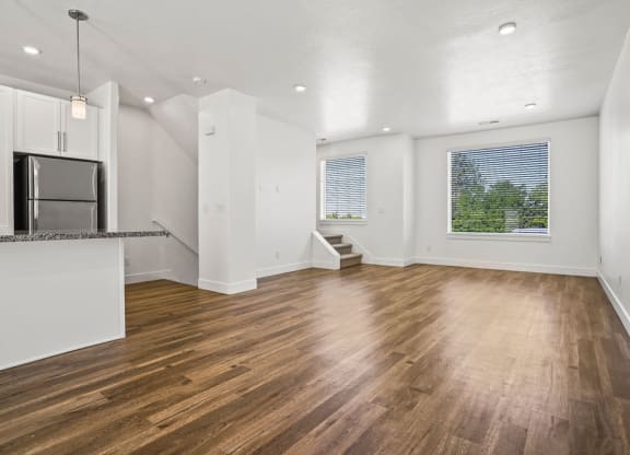 an empty living room and kitchen with wood floors and a refrigerator  at Aero Luxury Townhomes in Layton, Utah