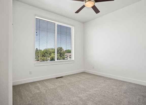an empty living room with a large window and a ceiling fan  at Aero Luxury Townhomes in Layton, Utah