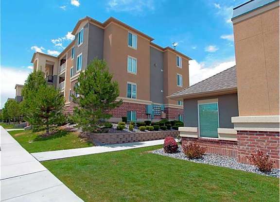 A large apartment complex with a well-maintained lawn and landscaping.