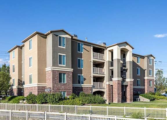 A large apartment building with a white picket fence in front.