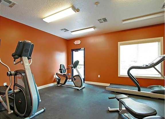 A gym with orange walls and a variety of exercise equipment.