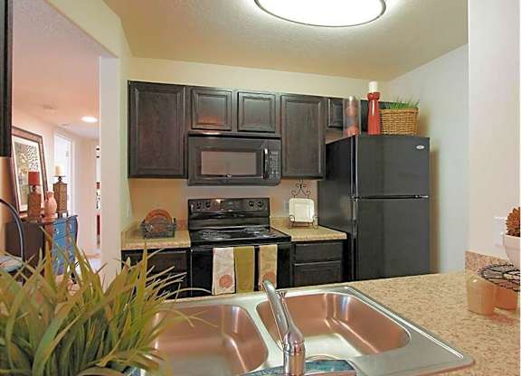 A kitchen with a stove, microwave, and refrigerator.