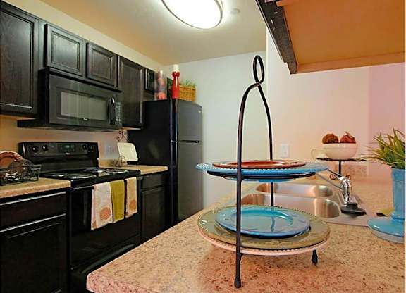 A kitchen with black cabinets and a black stove top oven.