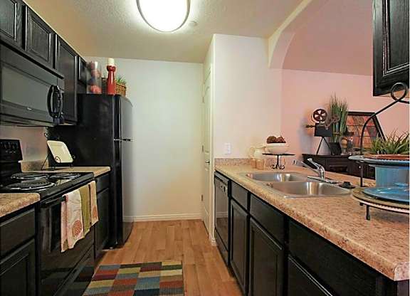 A kitchen with black cabinets and a black refrigerator.