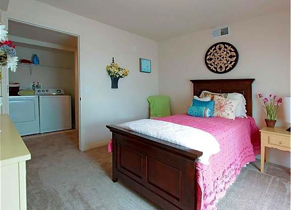 A bedroom with a pink bedspread and a wooden bed.