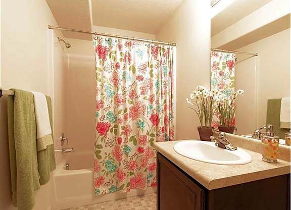 A bathroom with a floral shower curtain and a white sink.