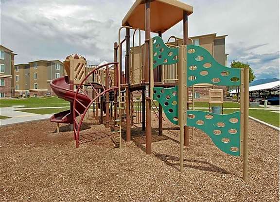A playground with a red slide and a green climbing structure.