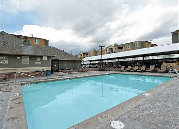 A large swimming pool with a concrete floor and a metal fence around it.