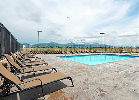 A pool surrounded by chairs and a fence.