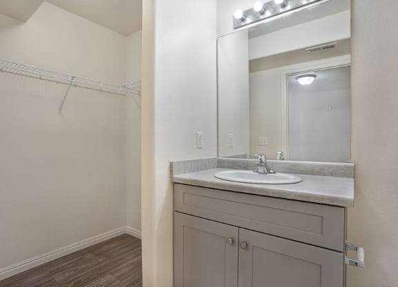 A bathroom with a sink, mirror, and wooden floor.