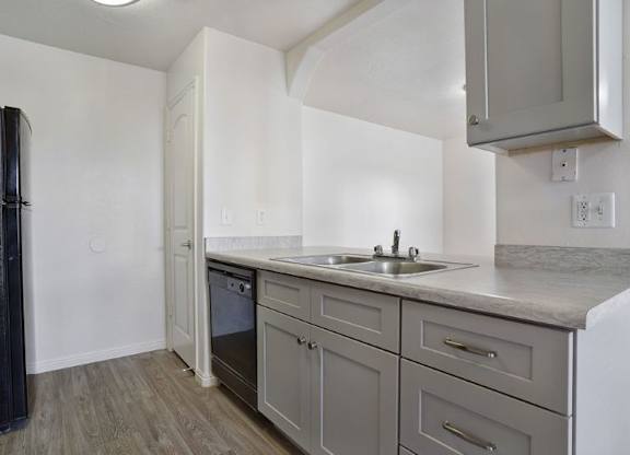 A kitchen with a black fridge, a sink, and a white dishwasher.