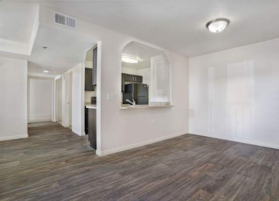 A room with wood flooring and a white wall.
