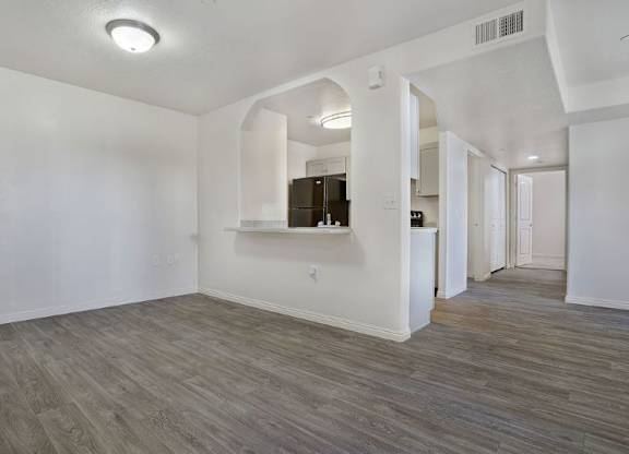 A spacious room with wood flooring and white walls.