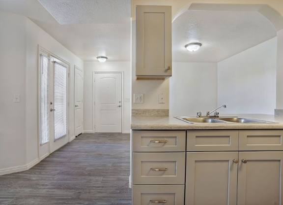 A kitchen with a sink, cabinets and a window.
