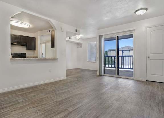 A spacious living room with a kitchen area in the background.