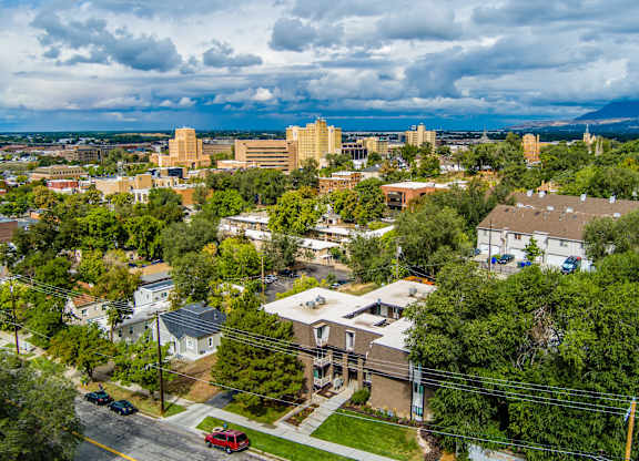 A cityscape with buildings and trees under a cloudy sky.