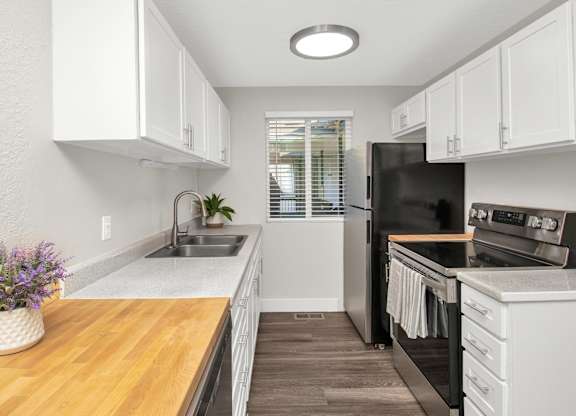 A kitchen with white cabinets and a black refrigerator.