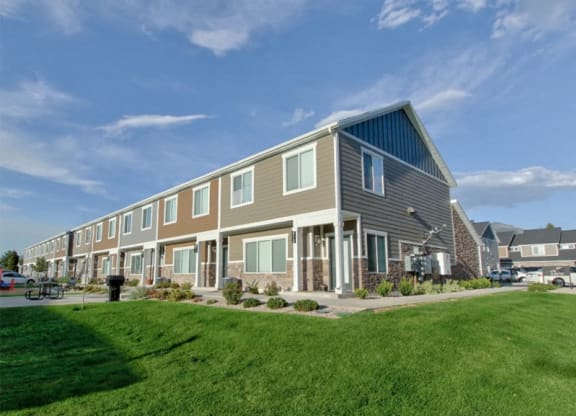 a row of houses with a green lawn and a blue sky