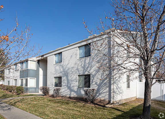 A modern building with a grey facade and a white fence in front.