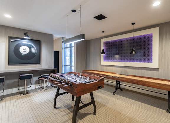 A room with a pool table and a purple wall hanging.