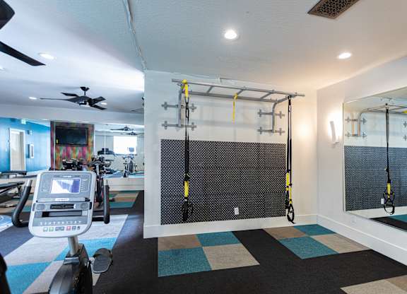 A gym with a treadmill, a wall-mounted mirror, and a wall-mounted pull-up bar.