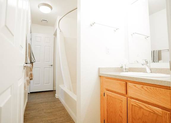 A bathroom with a wooden vanity and a white sink.
