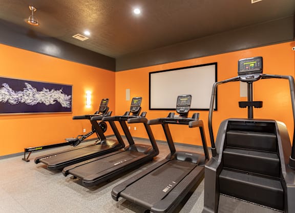 A gym with treadmills and a digital display.
