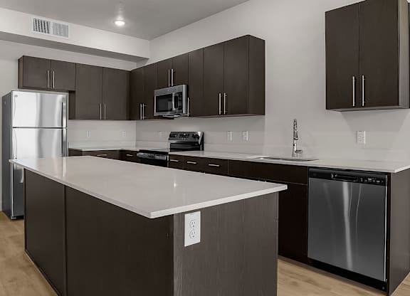 A modern kitchen with dark brown cabinets and a white countertop.