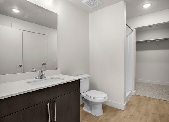 A white toilet sits in a bathroom with a sink and mirror.