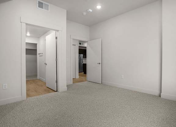 A white room with a carpeted floor and a doorway leading to another room.